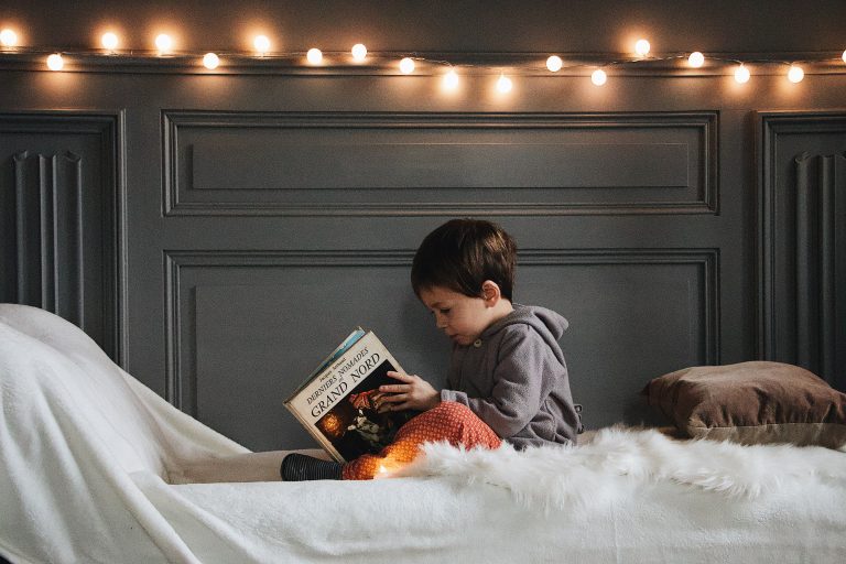 Kurze Weihnachtsgeschichten für Kinder Junge liest im Bett